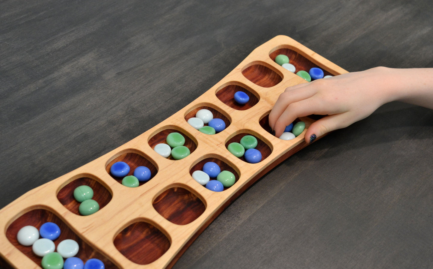child playing mancala game with handmade wooden board